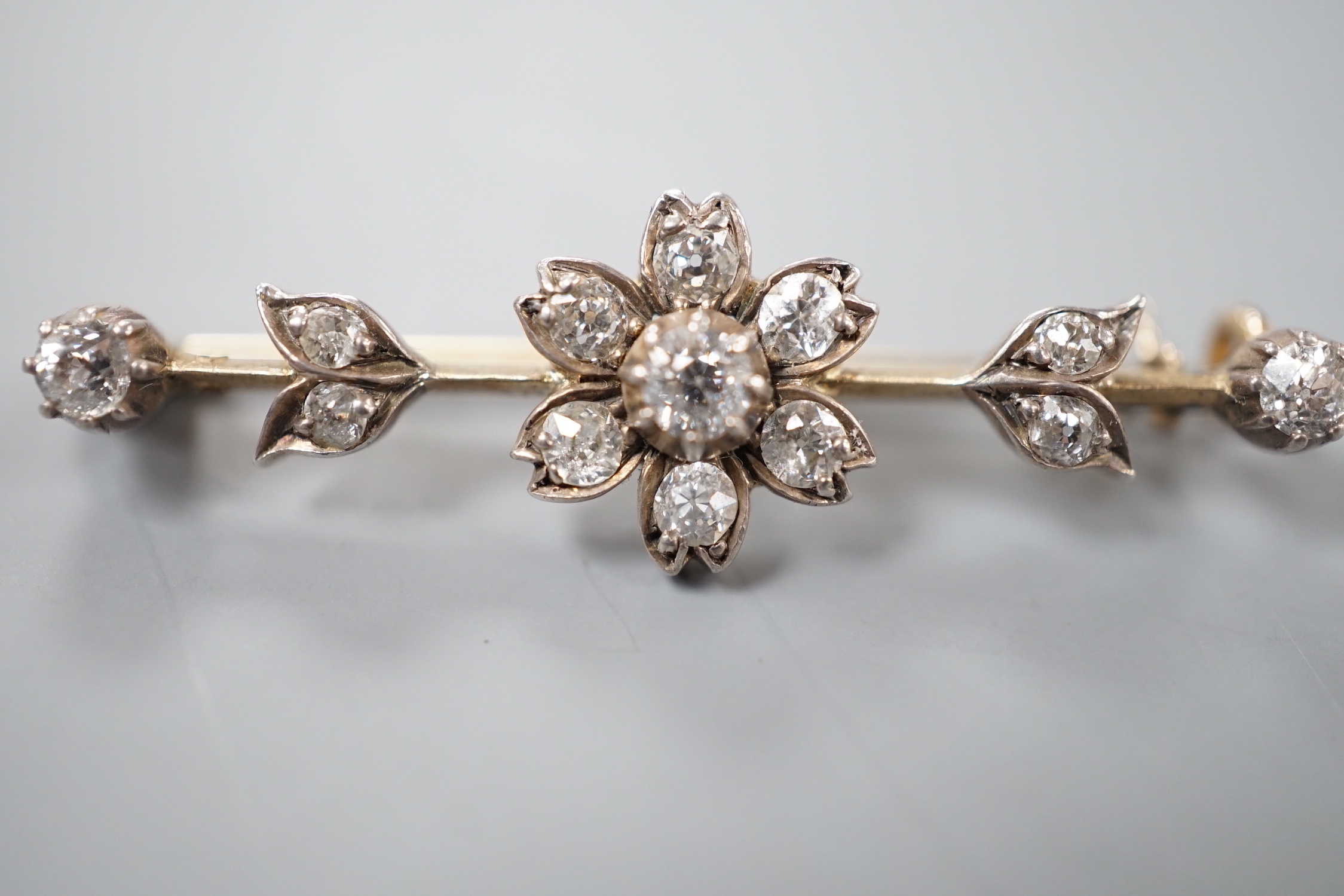 A Victorian yellow metal and diamond flowerhead cluster set bar brooch, 40mm, gross 3.8 grams.
